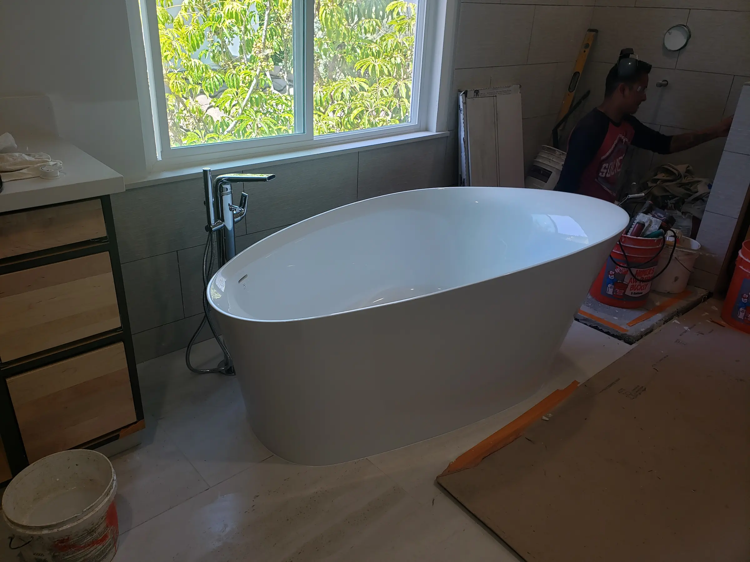 A modern freestanding bathtub in a bathroom under renovation.