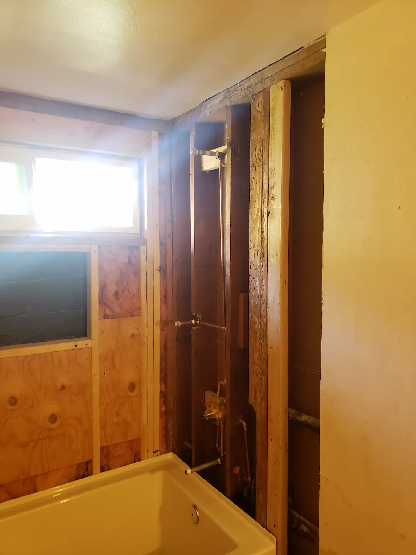 Bathroom under renovation with exposed wooden framing and bathtub.