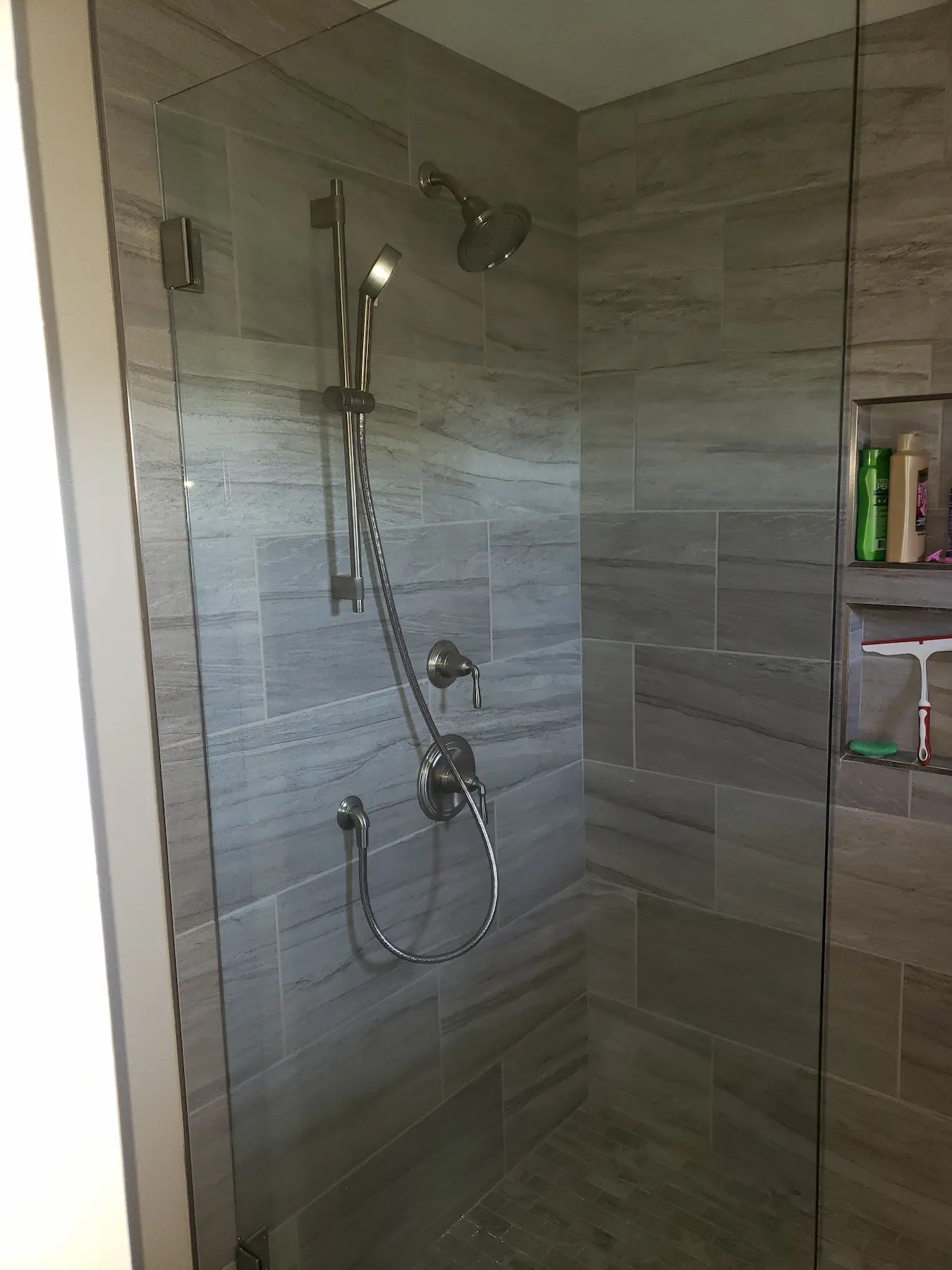 Modern shower with gray tiles and dual showerheads.