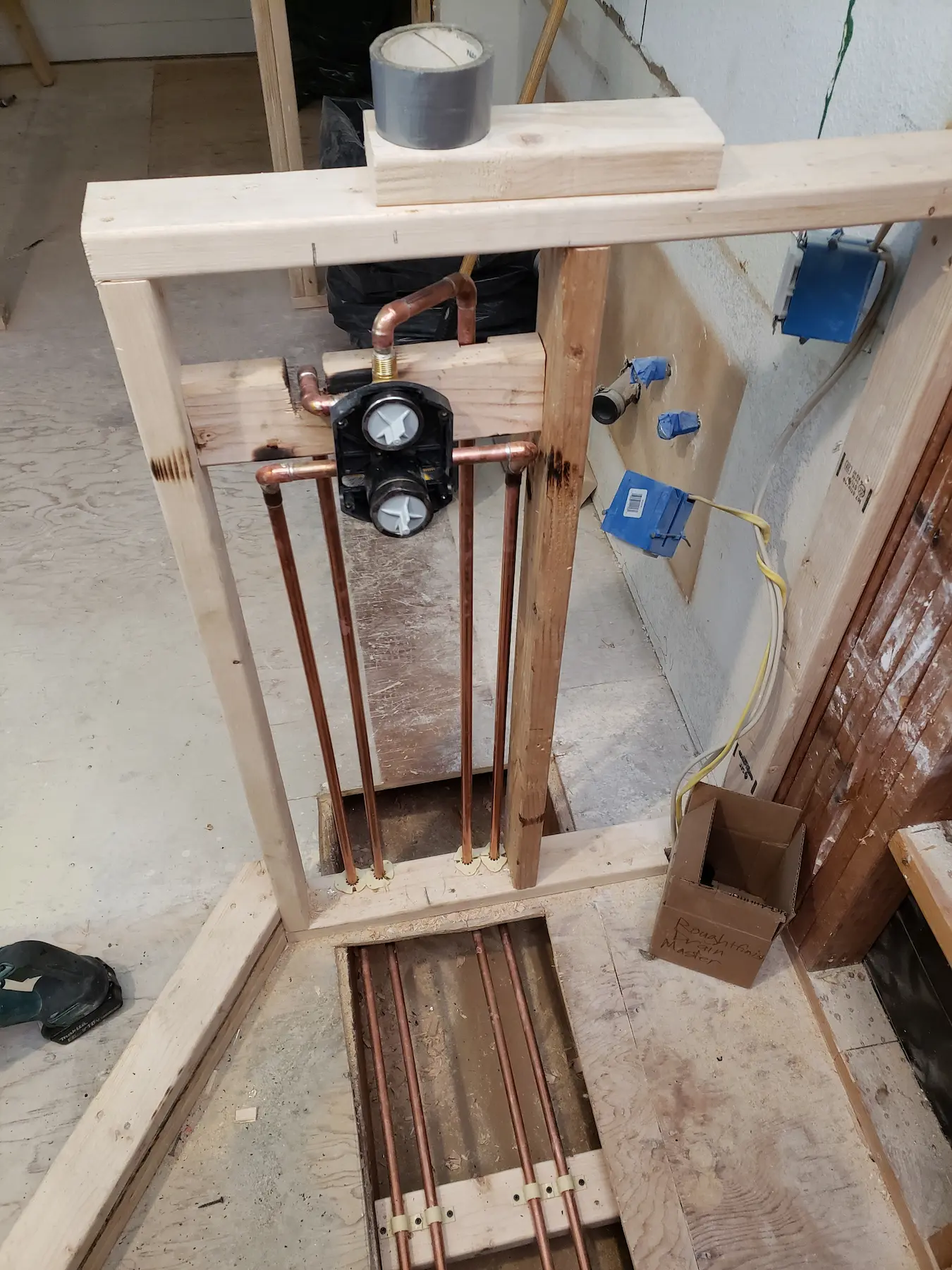 Copper plumbing pipes installed in wooden framing during construction.