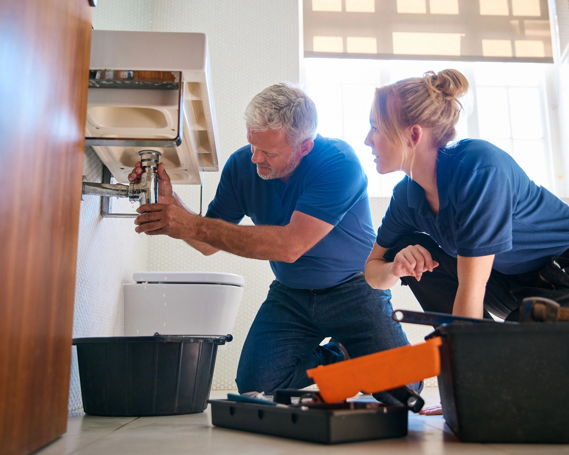 Male plumber fixing bathroom sink leak