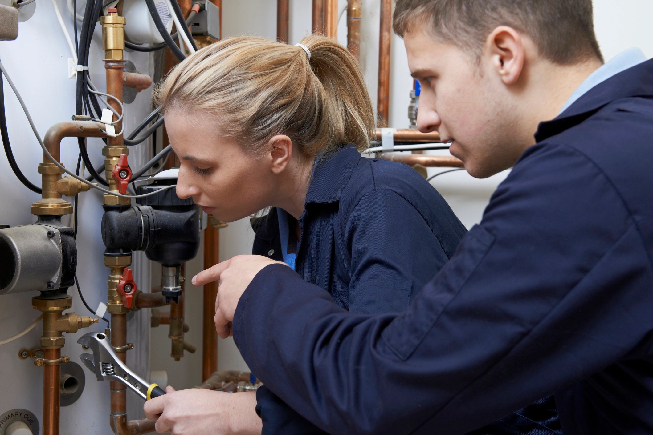 Female plumber repairing boiler